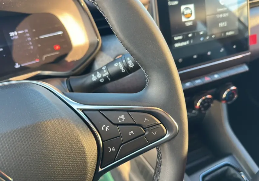 Gros plan sur le volant de la Renault Clio DCI 100 Evolution Camera 2025 avec commandes intégrées et tableau de bord numérique.