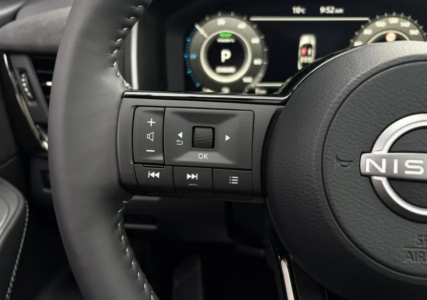 Gros plan sur le volant cuir noir du Nissan Qashqai 2025 avec commandes intégrées et tableau de bord numérique lumineux.