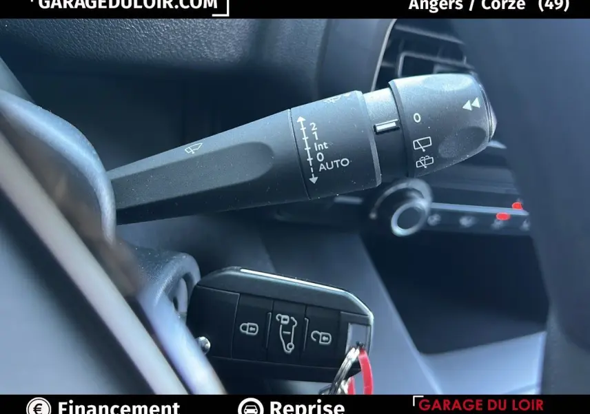 Gros plan sur la commande d'essuie-glace et la clé de contact dans l'habitacle d'un Peugeot Rifter bleu 2024.