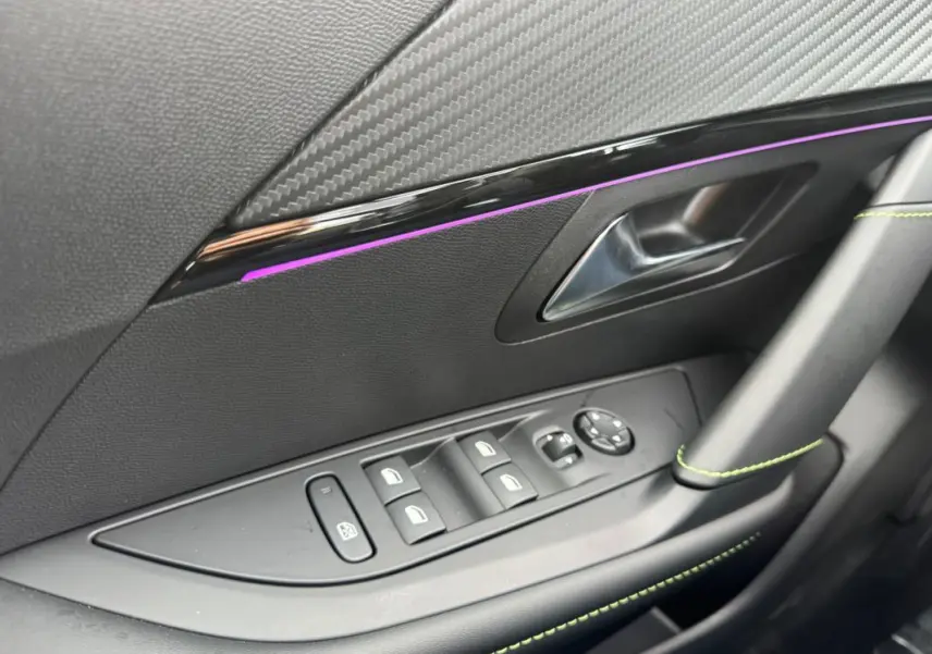 Détail de la porte côté gauche intérieure d'une Peugeot 208 Hybrid 110 gris, avec commandes vitres et insert décoratif noir brillant.