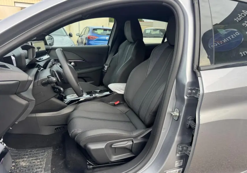 Intérieur avant droit d’une Peugeot 208 Hybrid 110 gris 2025, sièges noirs et tableau de bord moderne avec écran tactile.