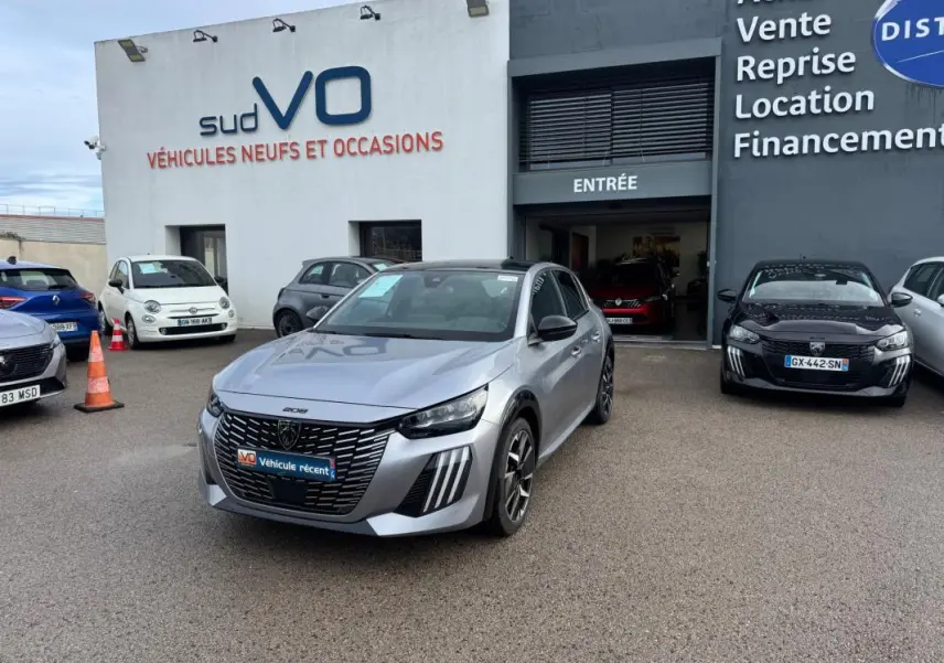 Peugeot 208 Hybrid gris vue 3/4 avant avec jantes alliage 17 pouces, stationnée devant un garage Sud VO.