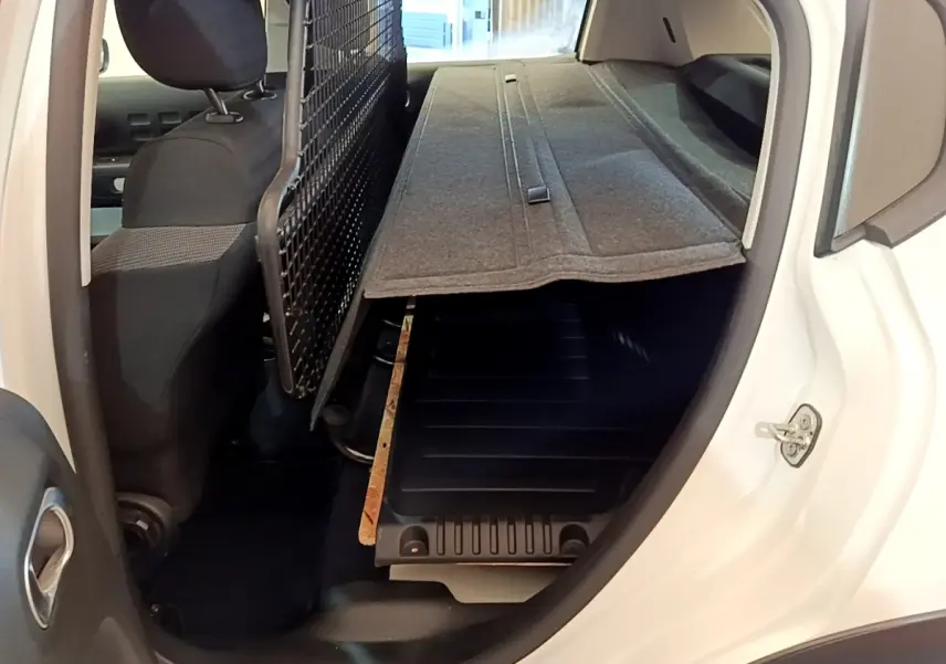 Vue intérieure côté droit du coffre blanc Citroën C3 2022 avec séparation grillagée et plancher modulable.