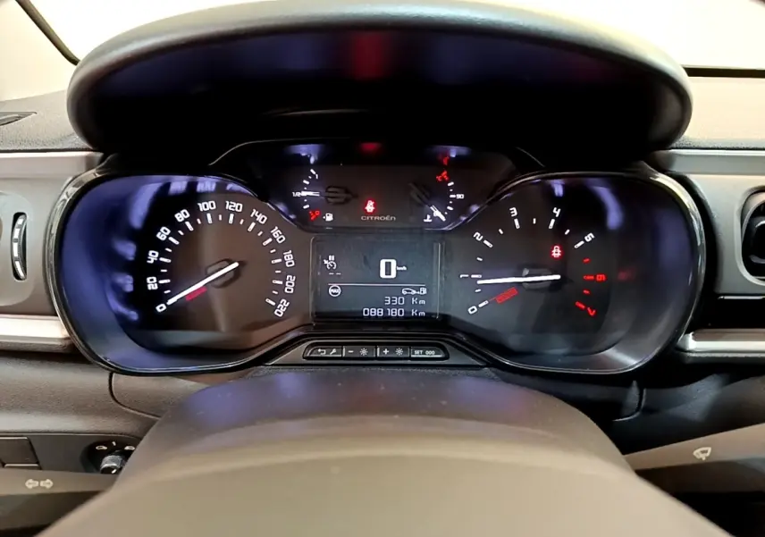 Vue rapprochée du tableau de bord de la Citroën C3 blanche, affichant le compteur et l'ordinateur de bord digital.