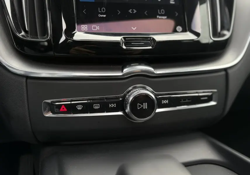 Gros plan sur la console centrale du Volvo XC60 2024, avec commandes multimédia et finition noire brillante.