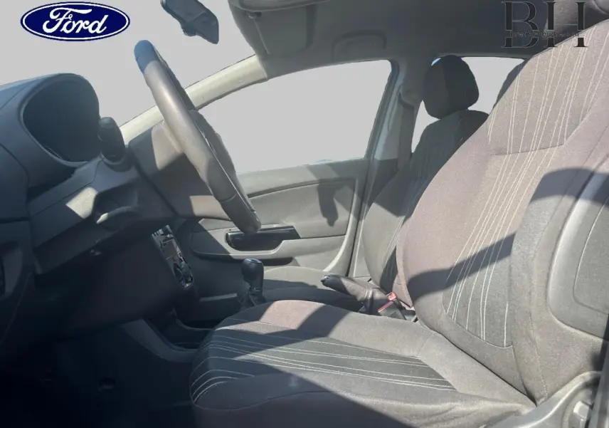 Vue intérieure côté conducteur de l'Opel Corsa noir 2010, montrant siège, volant et levier de vitesse manuel.