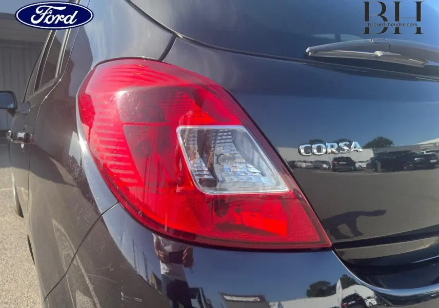 Gros plan sur le feu arrière droit d’une Opel Corsa noire de 2010, avec le logo Corsa visible sur le hayon.