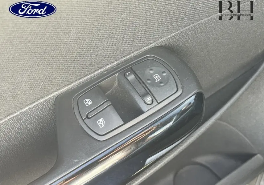 Gros plan sur les commandes de lève-vitres et réglage des rétroviseurs côté conducteur d'une Opel Corsa noire, vue intérieure.