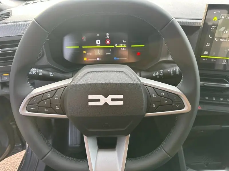 Vue frontale du volant multifonction du Dacia Duster 1.8 hybrid 155ch Journey avec tableau de bord numérique et écran tactile.