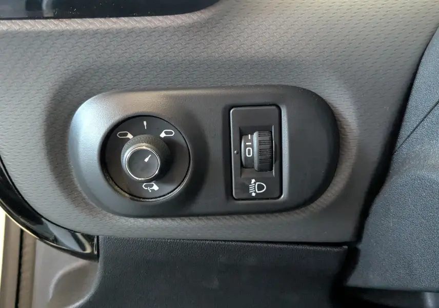 Gros plan sur les commandes de réglage des rétroviseurs et des phares du tableau de bord d'une Citroën C4 Cactus blanche 2019.