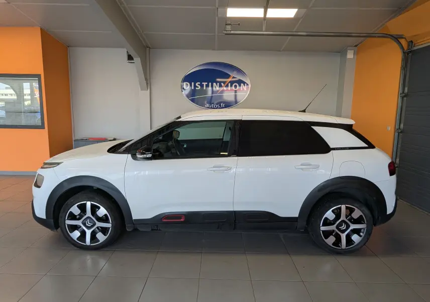Profil côté gauche d'une Citroën C4 Cactus blanche 2019 avec jantes bi-ton et protections noires sur les bas de caisse.