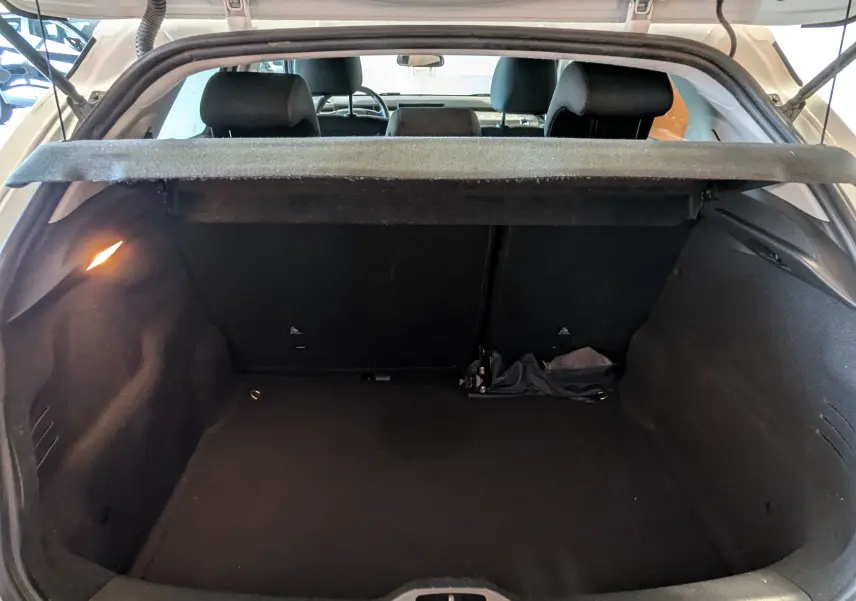 Coffre ouvert vu de l'arrière d'une Citroën C4 Cactus blanche, intérieur noir avec cache-bagages relevé.