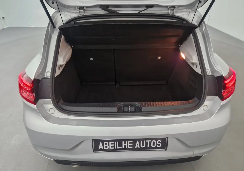 Coffre ouvert vu de l'arrière d'une Renault Clio V gris platine, avec feux arrière allumés et plaque Abeilhe Autos.