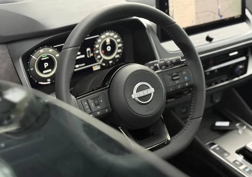 Vue rapprochée du volant cuir noir du Nissan Qashqai 2025 avec commandes intégrées et tableau de bord numérique.