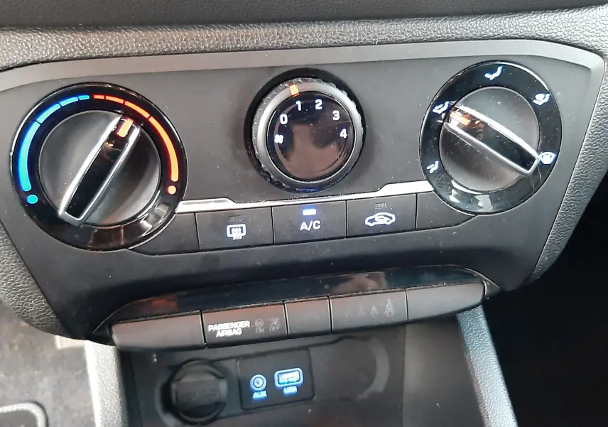 Vue rapprochée du tableau de commande de climatisation et connectiques USB/AUX d'une Hyundai i20 blanche de 2016.