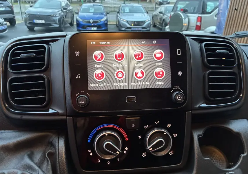 Vue intérieure centrée sur l’écran tactile et la console de climatisation du Fiat Ducato Fourgon blanc 2025.