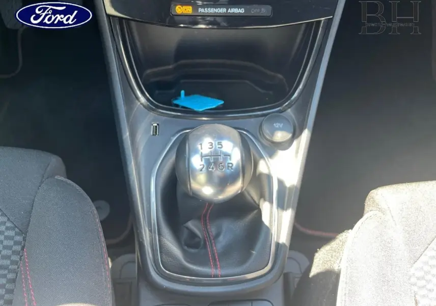 Le levier de vitesses manuel du Ford Puma 2024, avec soufflet noir et surpiqûres rouges, vu de dessus entre les sièges.