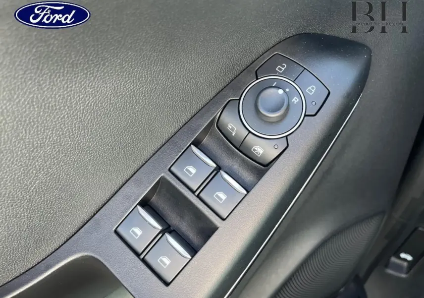 Gros plan sur les commandes de lève-vitres et rétroviseurs côté conducteur du Ford Puma 2024 gris Solar Métallisée.