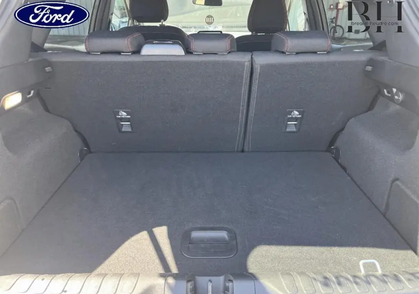 Vue intérieure du coffre spacieux du Ford Puma 2024 gris Solar Métallisée, avec banquette arrière rabattue et habillage noir.