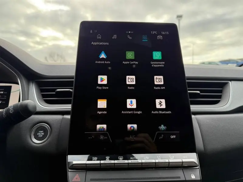 Vue intérieure centrée sur l'écran tactile multimédia du Renault Captur 2025, avec tableau de bord et bouton start/stop visibles.