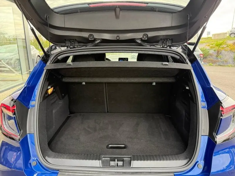 Coffre ouvert vu de l'arrière d'un Renault Captur 2025 Bleu Iron/Noir Etoilé, montrant l'espace de chargement vide.