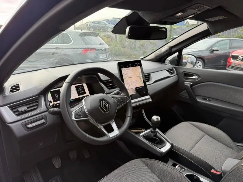 Vue intérieure côté conducteur du Renault Captur 2025, tableau de bord moderne avec écran tactile vertical et boîte manuelle.
