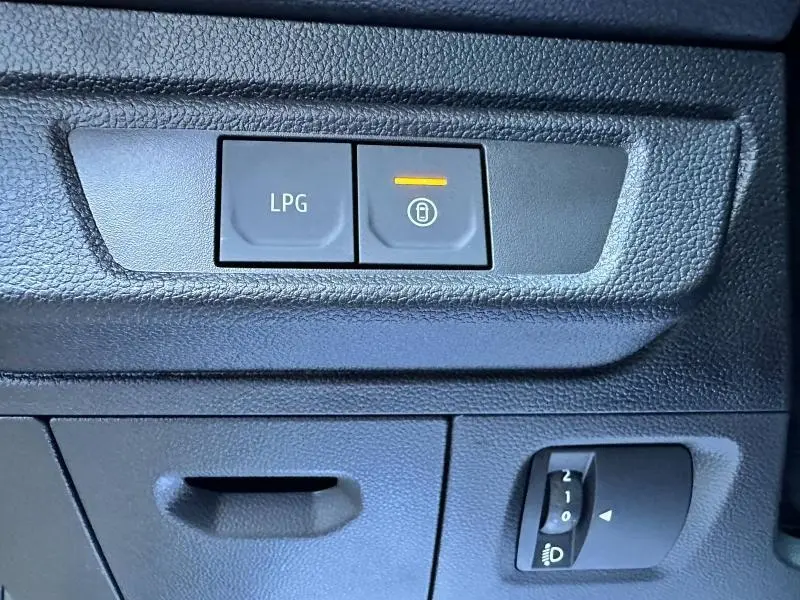 Gros plan sur les boutons de commande LPG et verrouillage centralisé du tableau de bord noir du Dacia Sandero beige Safari 2025.