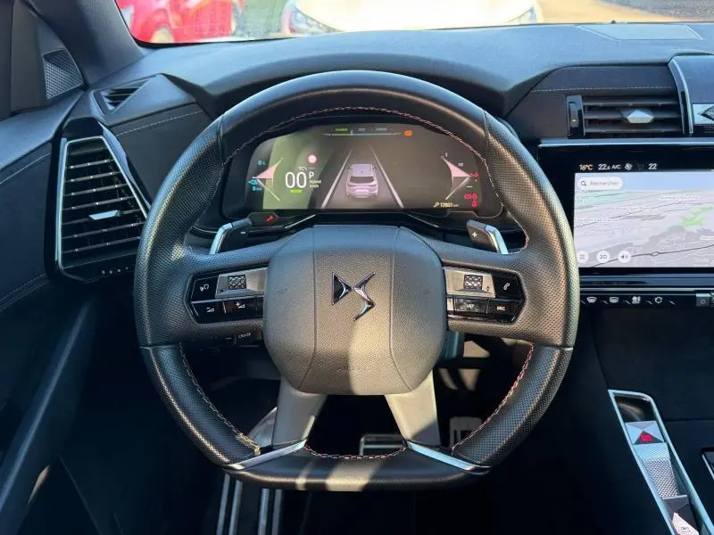 Vue intérieure centrée sur le volant DS d'un DS7 E-TENSE 225ch 2024 avec tableau de bord numérique et écran tactile.