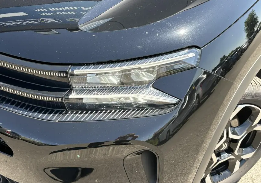 Gros plan sur le phare avant droit noir Perla du Citroën C5 Aircross Hybrid 2025 avec jante alliage 18 pouces.