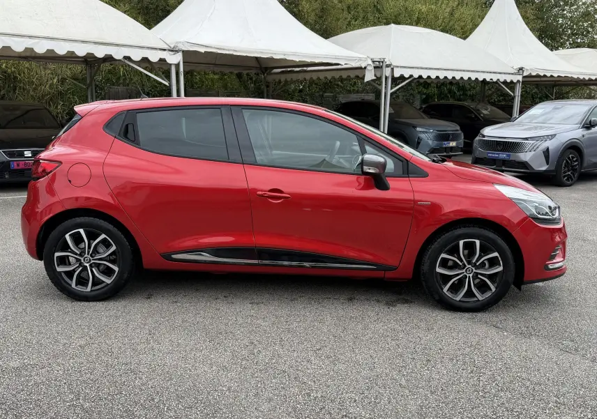 Profil droit d'une Renault Clio IV Limited TCe 90 rouge flamme, avec jantes alliage et détails noirs sur les bas de caisse.