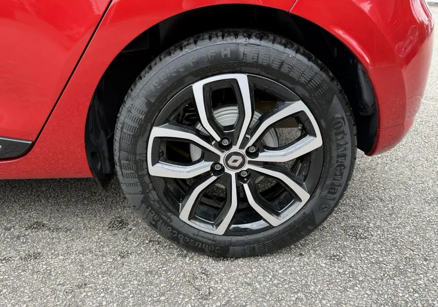 Gros plan sur la roue avant droite d'une Renault Clio IV Limited TCe 90 rouge flamme avec jante alliage noire et argent.
