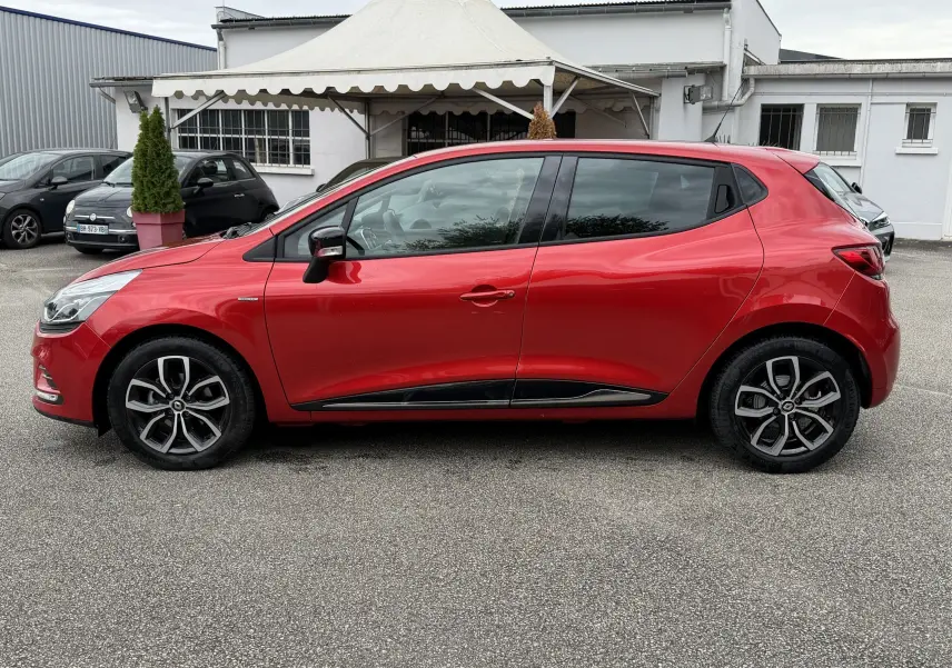 Profil côté gauche d'une Renault Clio IV Limited TCE 90 rouge flamme de 2017 avec jantes alliage et vitres teintées.