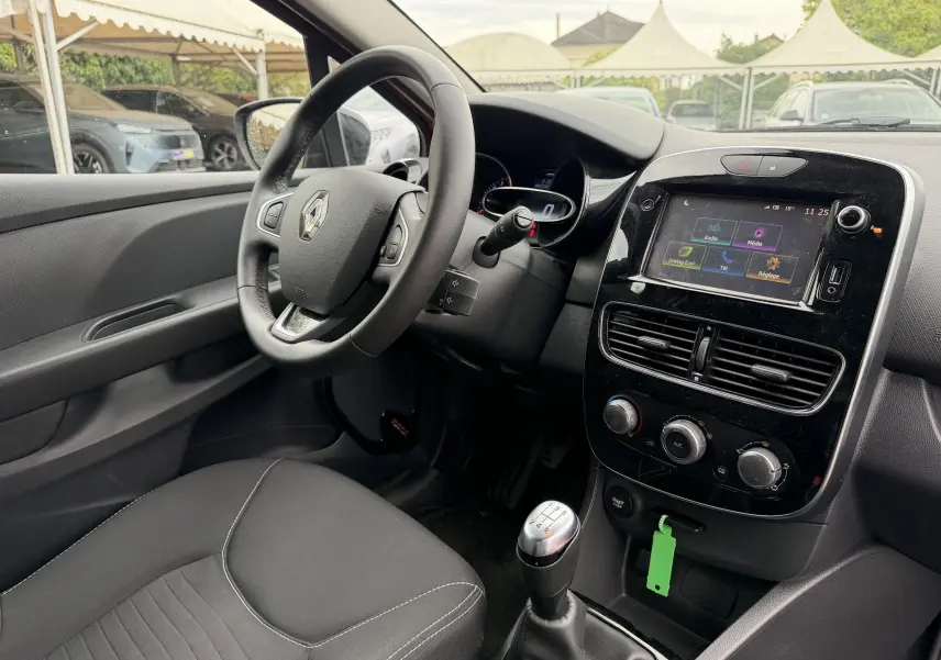 Vue intérieure côté conducteur de la Renault Clio IV Limited TCe 90, volant cuir, écran tactile et levier de vitesses manuel.