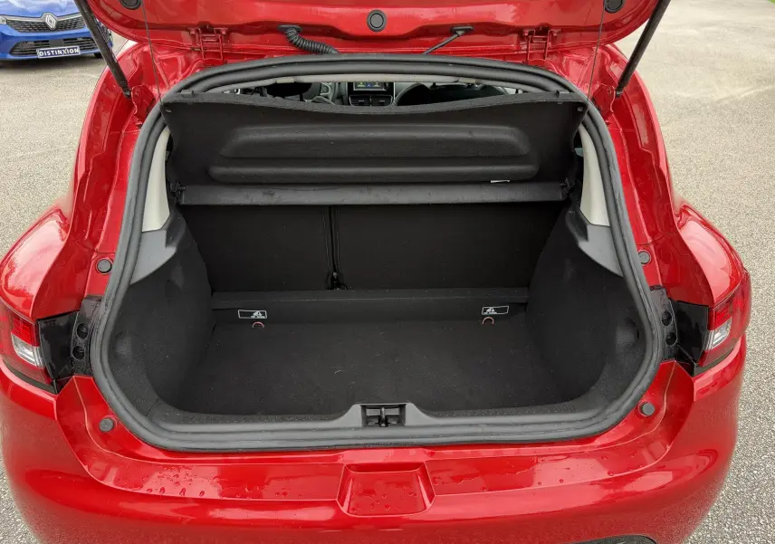 Coffre ouvert vu de l'arrière d'une Renault Clio IV Limited TCe 90 rouge flamme, intérieur de coffre noir vide.