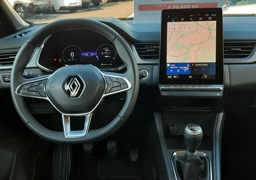 Vue intérieure frontale du tableau de bord du Renault Captur 2024, volant multifonction et écran tactile vertical.