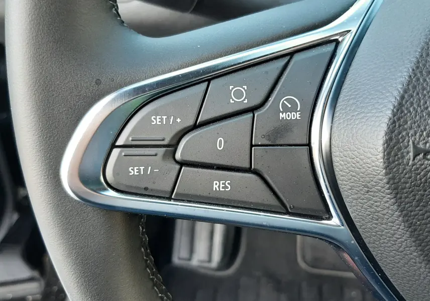 Gros plan sur les commandes de régulateur de vitesse au volant noir du Renault Captur 2024.