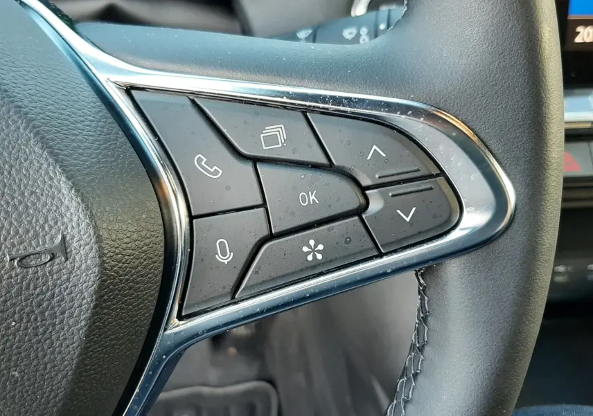 Gros plan sur les commandes multifonctions à droite du volant cuir noir du Renault Captur 2024 biton noir métal et toit gris.