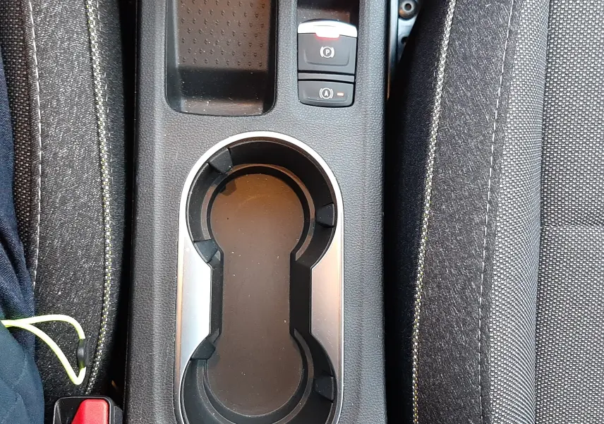 Vue plongeante sur la console centrale noire du Renault Captur 2024, avec porte-gobelets et bouton frein à main électrique.