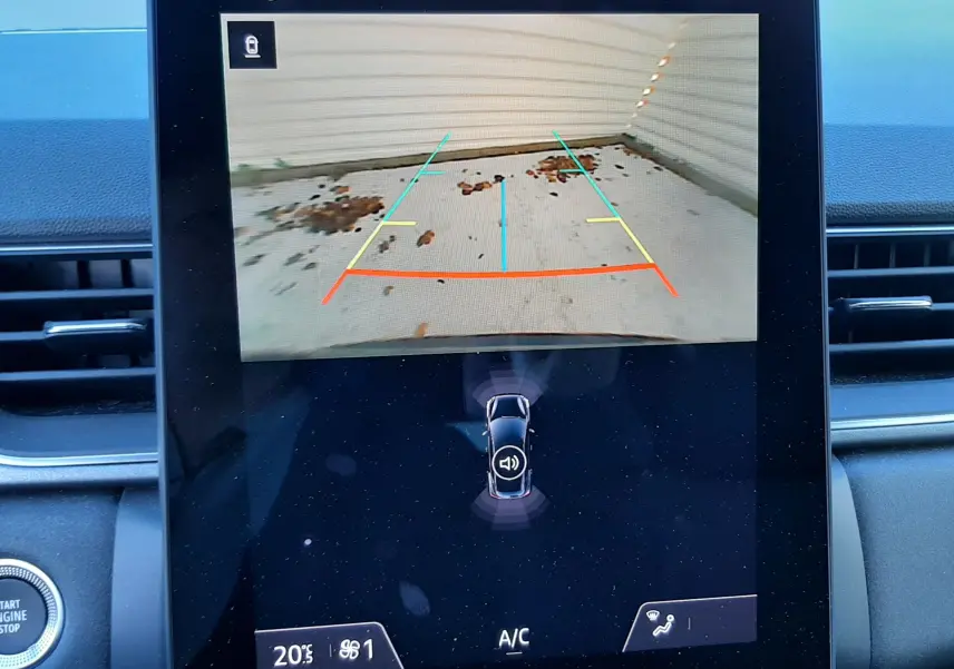 Écran central affichant la caméra de recul du Renault Captur 2024, avec lignes de guidage colorées et tableau de bord noir.