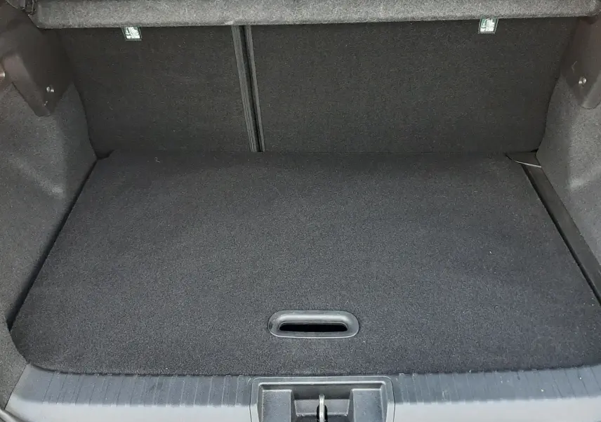 Coffre ouvert vu de l'arrière d'un Renault Captur 2024 noir métal avec toit gris, montrant un espace de chargement propre et vide.