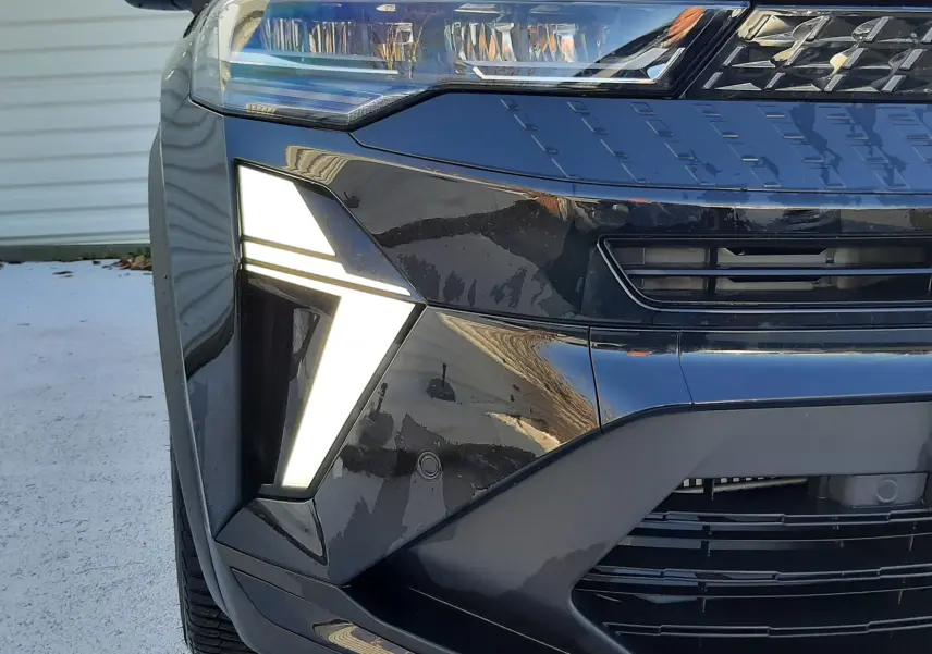 Gros plan sur le phare avant gauche du Renault Captur 2024 noir métal avec éclairage LED en forme de flèche.