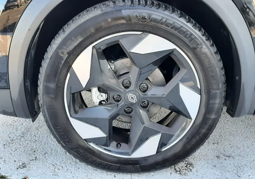 Gros plan sur la roue avant gauche du Renault Captur 2024 noir métal avec jante alliage bicolore au design étoilé.