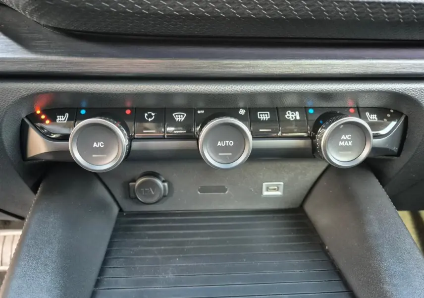 Gros plan sur la console centrale de la Citroën C5 X 2024 noire, montrant les commandes de climatisation automatique et les ports USB et 12V.