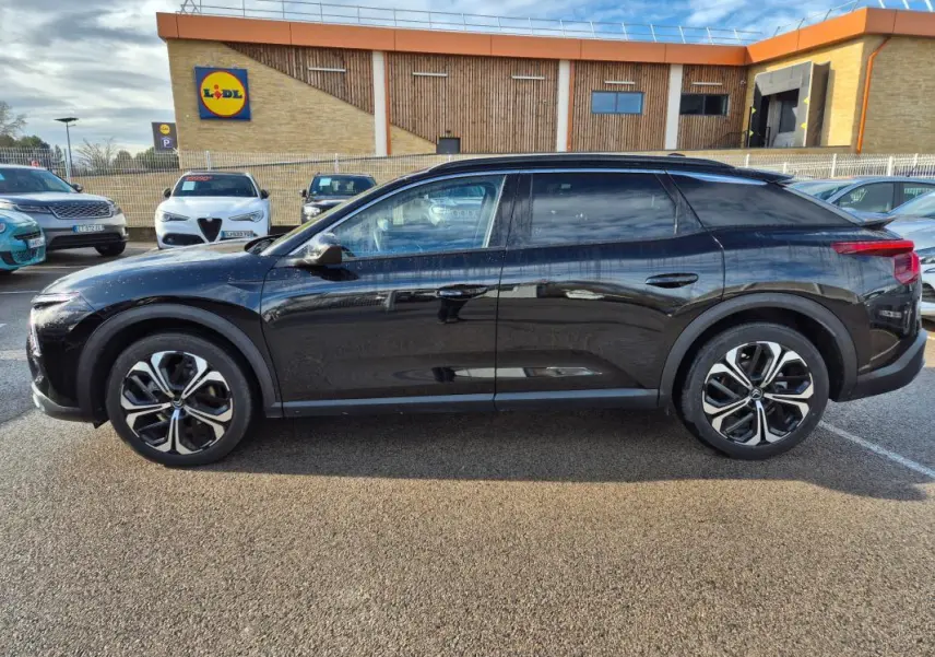 Vue latérale droite d'une Citroën C5 X noire 2024 avec jantes alliage 19 pouces, stationnée en extérieur.
