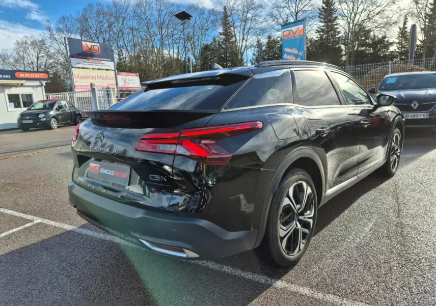 Vue 3/4 arrière droite d'une Citroën C5 X noire 2024 avec jantes alliage 19 pouces et antenne requin.