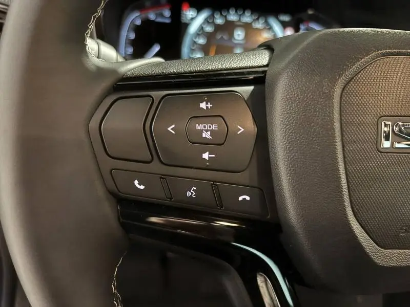Gros plan sur les commandes audio et téléphone au volant cuir du pick-up Isuzu D-MAX 2025, finition Nitro Sport.
