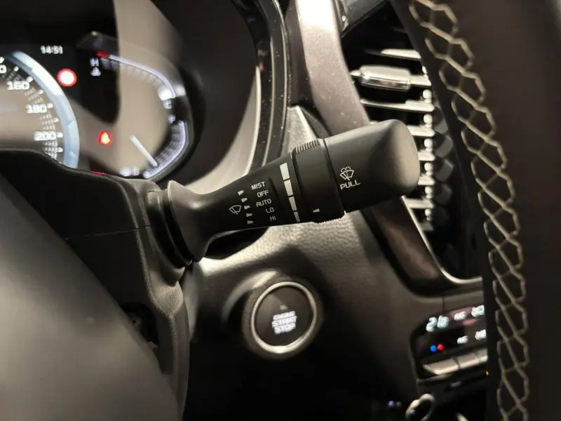 Gros plan sur la commande d'essuie-glace à gauche du volant dans l'habitacle noir du pick-up Isuzu D-MAX Biarritz Blue 2025.