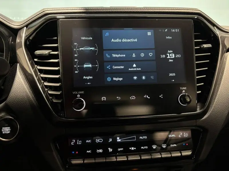 Écran tactile central du tableau de bord de l'Isuzu D-MAX 2025 avec commandes climatisation et bouton start/stop visibles.