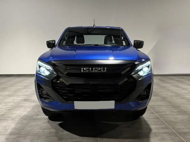 Vue frontale du pick-up Isuzu D-MAX 2025 en Biarritz Blue Metallic avec phares LED allumés dans un intérieur neutre.