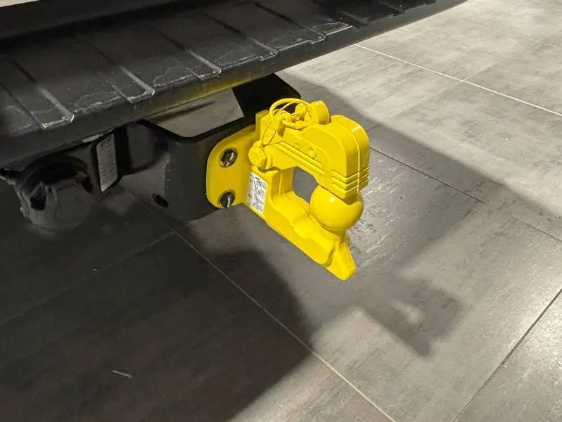 Gros plan sur l'attelage de remorque jaune fixé à l'arrière d'un Isuzu D-MAX 2025 Biarritz Blue Metallic.